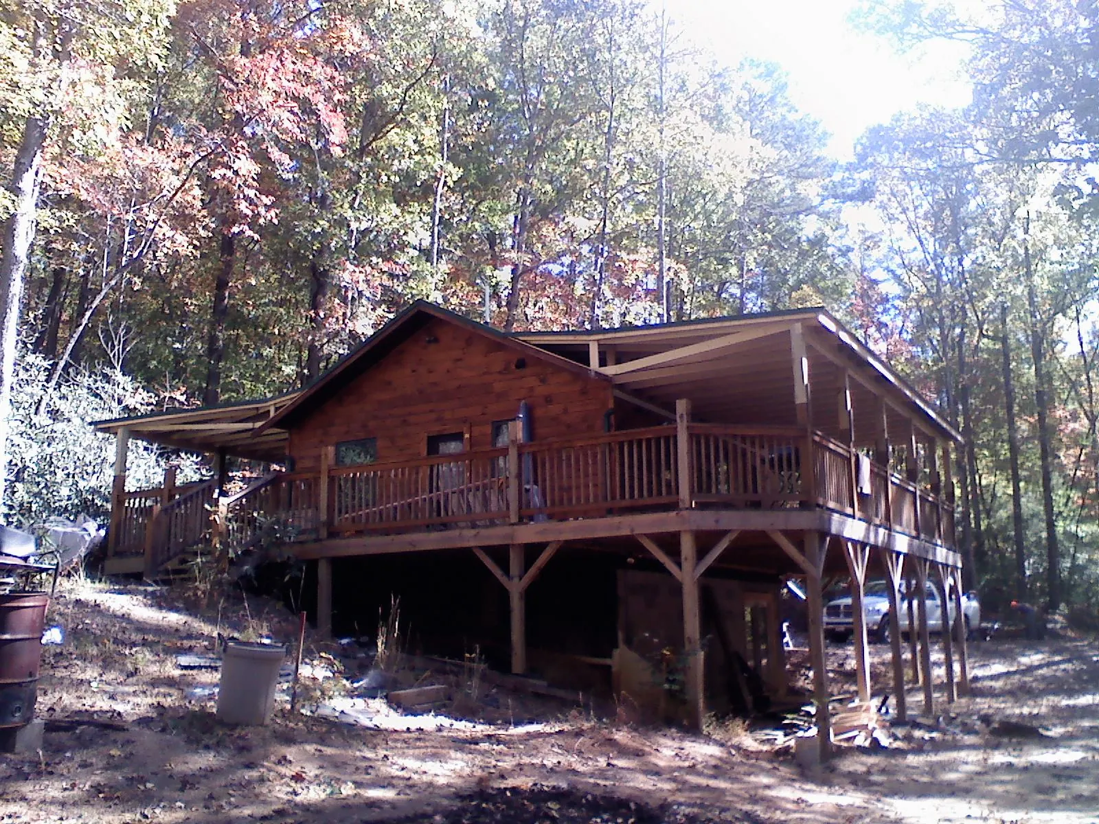 Log cabin with a wraparound porch and metal roof in the fall in Titusville