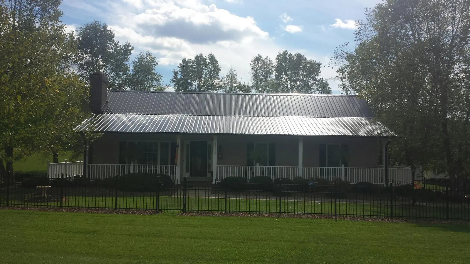 Gray metal roof on a brick ranch with a full width front porch — Gutter Guard Installation work by our crew in Titusville